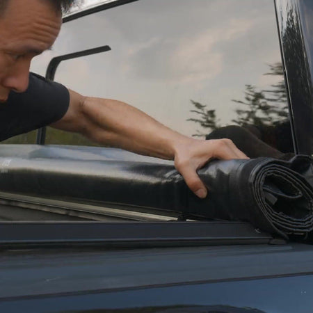 Rolling open a titan Soft Roll-Up tonneau cover by hand on a pickup truck